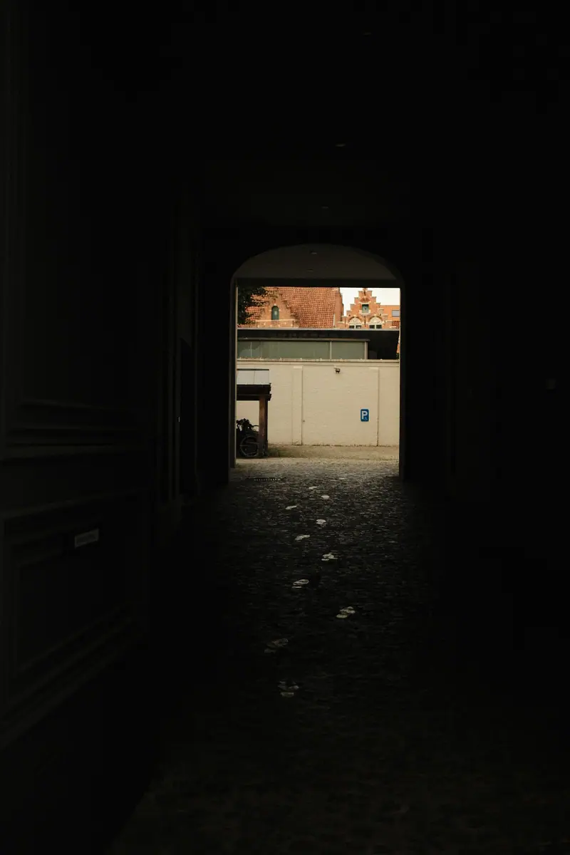 A dark stone passage opening onto a sunlit courtyard