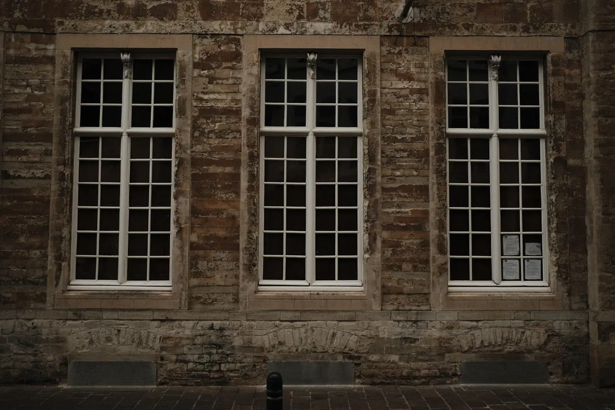 Three tall white-framed windows in a weathered stone wall