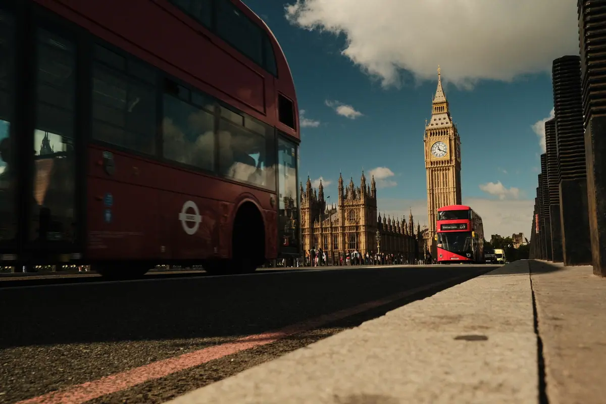 A red double-decker bus passes in the foreground with Big Ben ahead