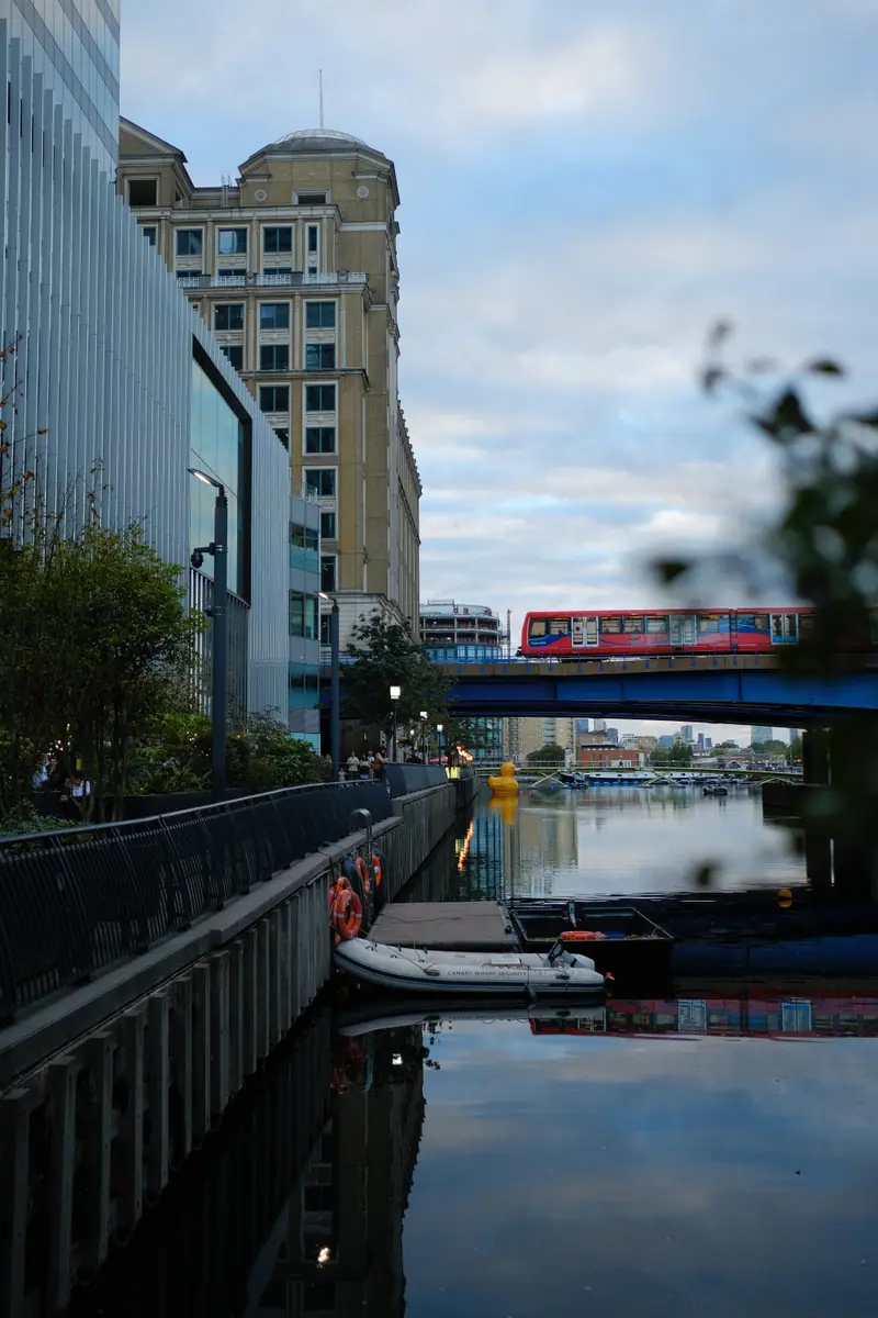 A red DLR train crosses a bridge above the still docks at Canary Wharf