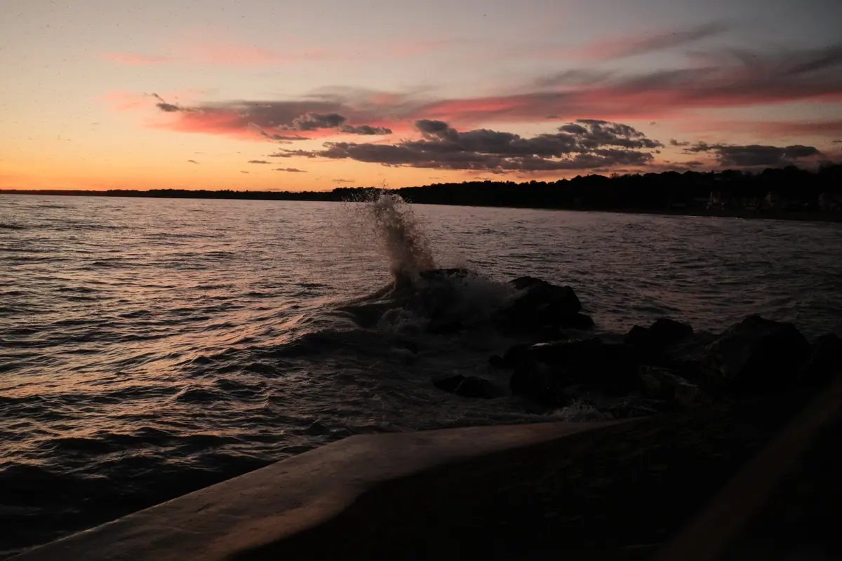 A wave breaks against the rocks at sunset on Lake Erie