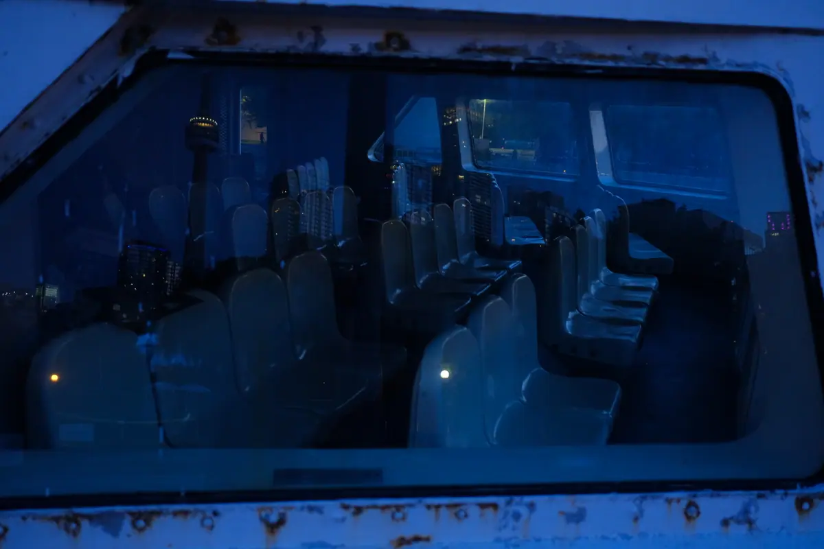 Rows of empty seats seen through a scratched boat window at blue hour