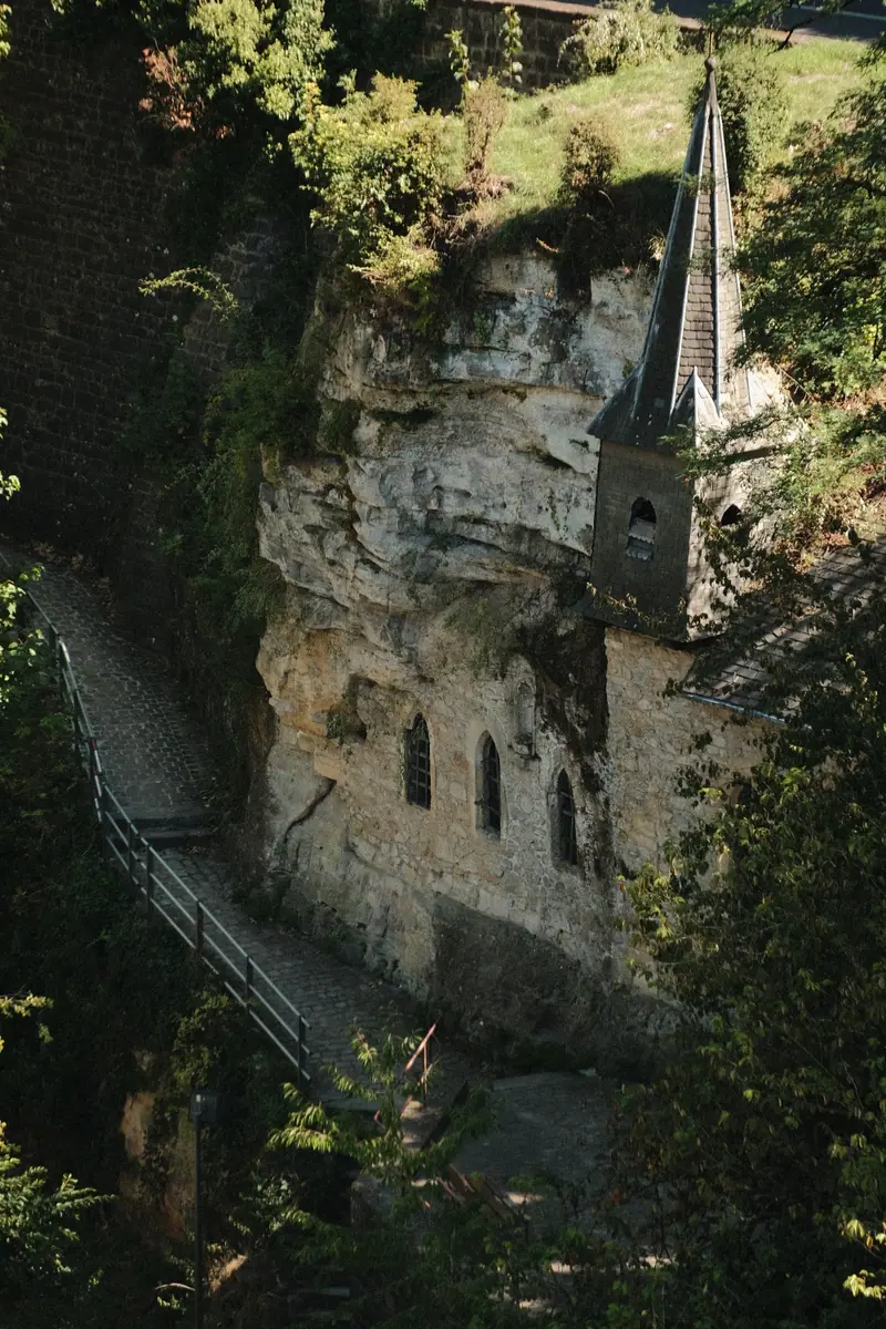A small church built into a cliff face, a stone stair climbing beside it