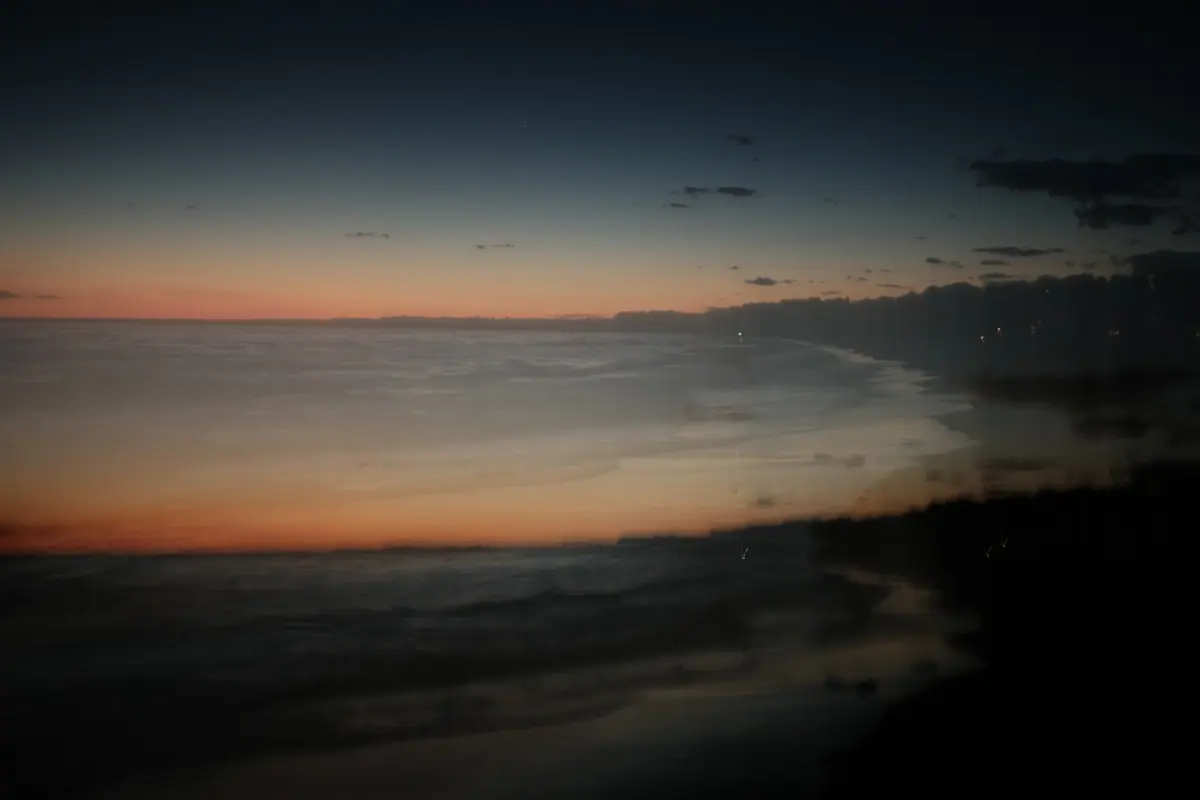 A blurred shoreline under a thin orange band of sunset