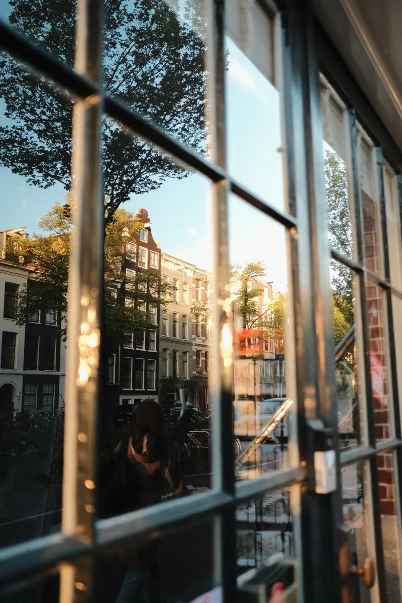 Canal houses glowing gold, reflected in the panes of an open window